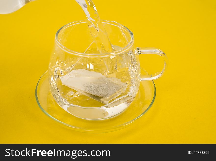 Tea cup and hot water on yellow background