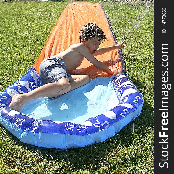 Boy riding down the water slide at home backyard. Boy riding down the water slide at home backyard.