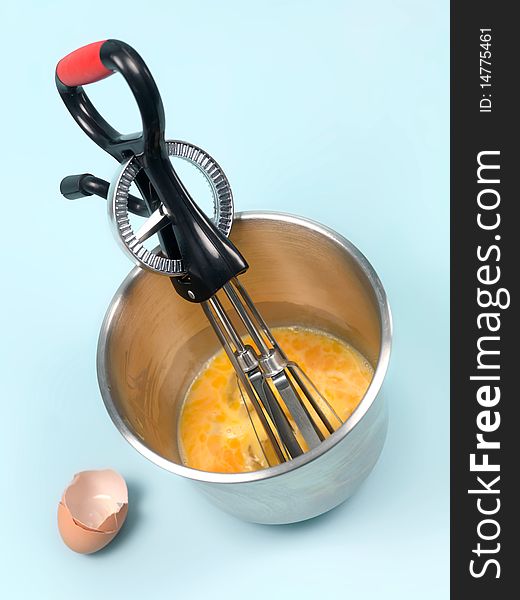 An egg beater eggs and a mixing bowl on a kitchen bench