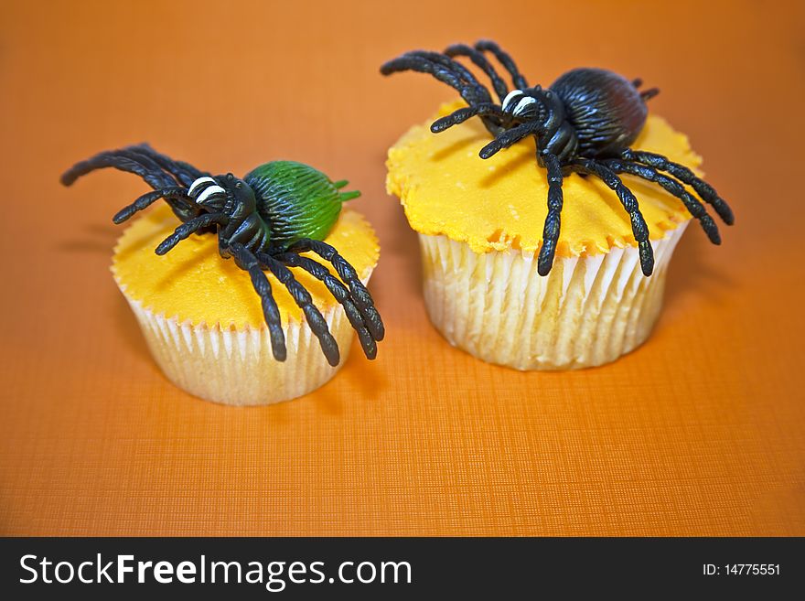 Creepy spiders on top of orange frosted cupcakes on orange background. Creepy spiders on top of orange frosted cupcakes on orange background.