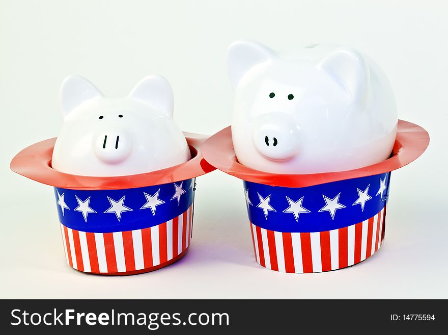 Two patriotic piggy banks sitting inside of stars and stripes hats on a white background.