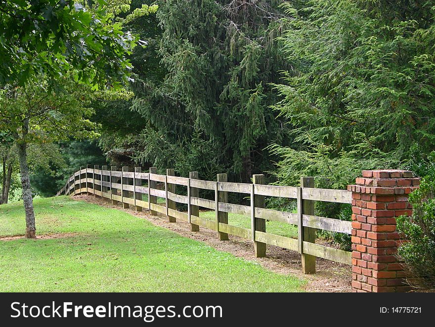 Rail fence and brick pillar, with trees in the background