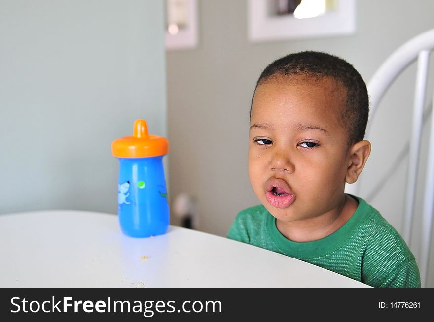 Boy at table enjoying drink with comical face to show he enjoy it. Boy at table enjoying drink with comical face to show he enjoy it