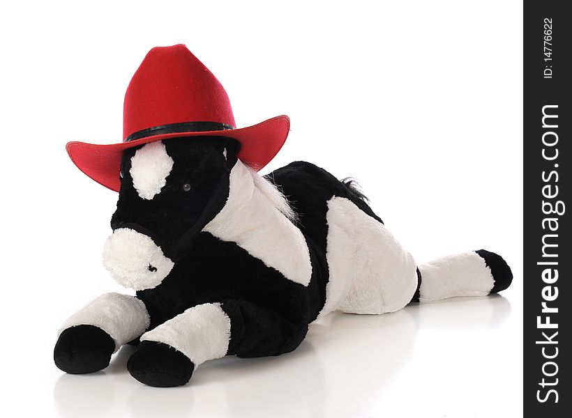 A toy horse wearing a child's bright red cowboy hat. Isolated on white. A toy horse wearing a child's bright red cowboy hat. Isolated on white.