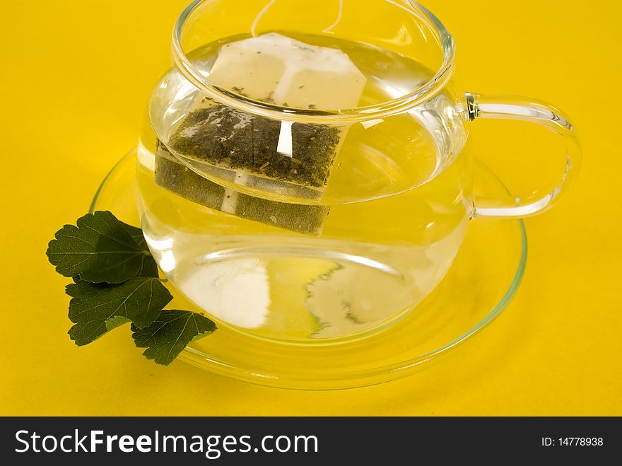 Transparent tea cup on yellow background