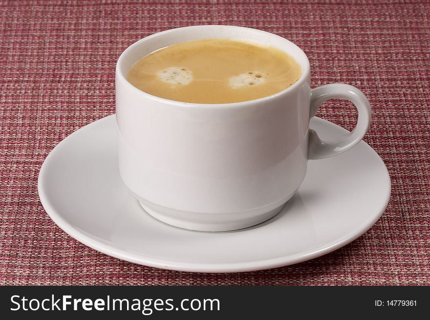 Little white espresso coffee cup on a white saucer over checked table-cloth background