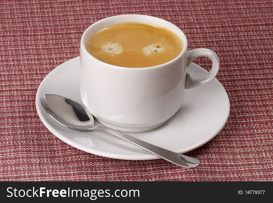 Little white espresso coffee cup on a white saucer over checked table-cloth background