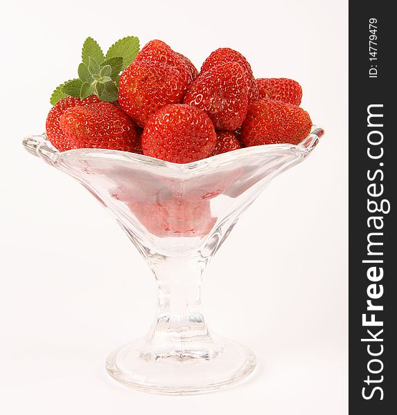 Strawberries in a cup decorated with a lemon balm twig on white background