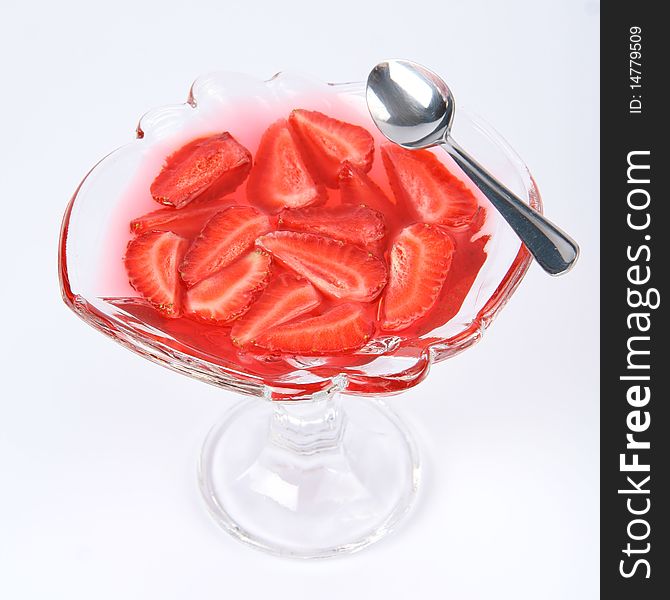 Jelly with strawberries in a glass cup with a spoon