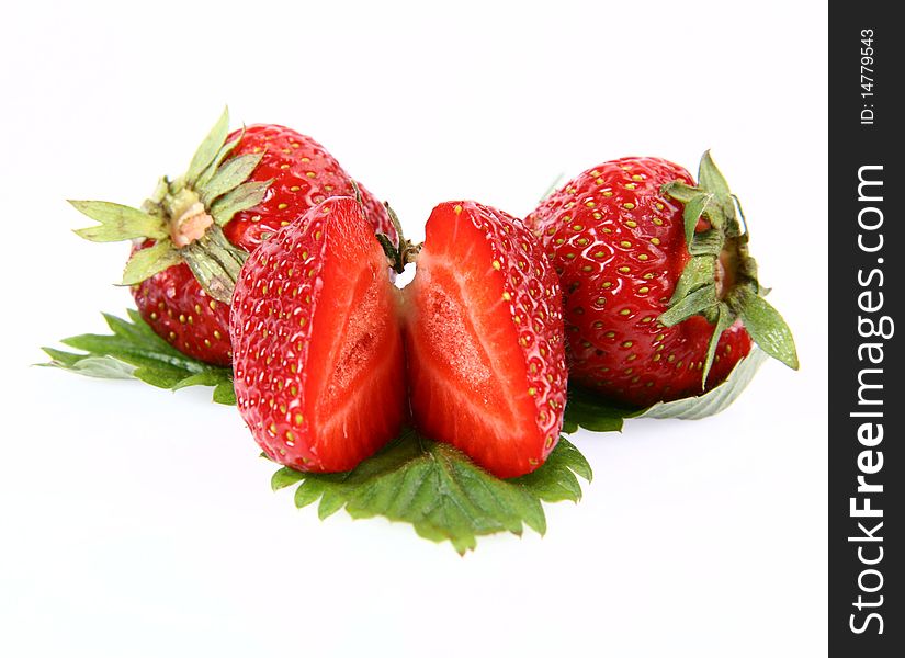 Strawberries on a leaf, one cut in half, on white background