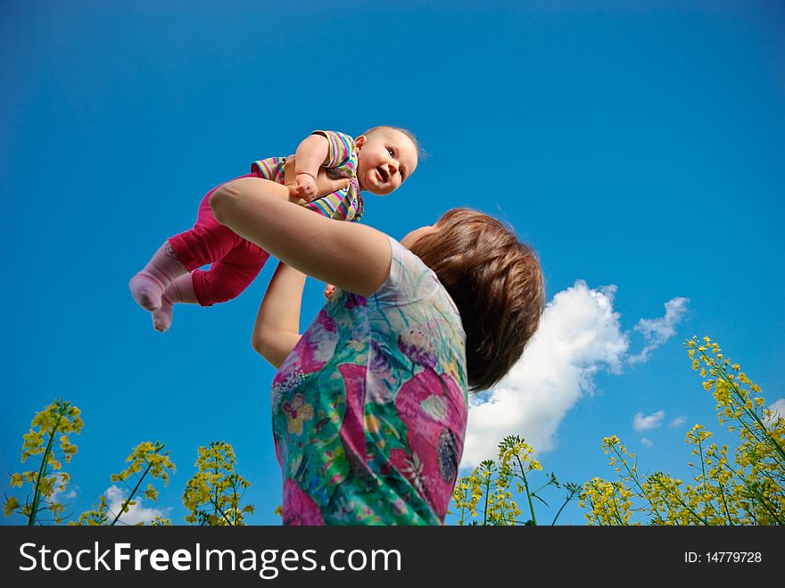 Baby flying above spring field flowers in mothers arms. Baby flying above spring field flowers in mothers arms