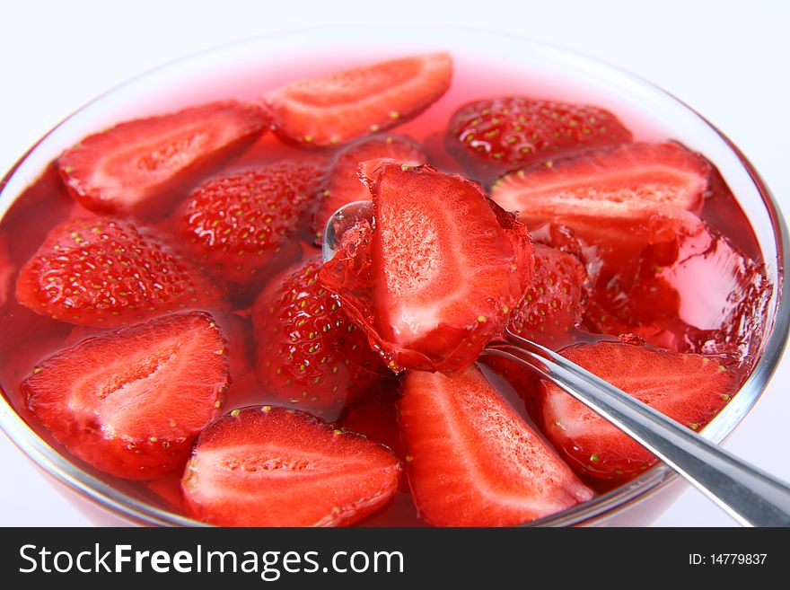 Jelly with strawberries, some of it on a spoon