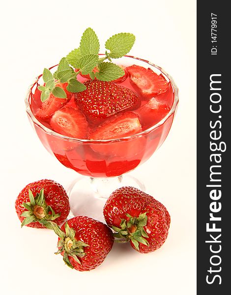 Jelly with strawberries decorated with a lemon balm twig and three strawberries