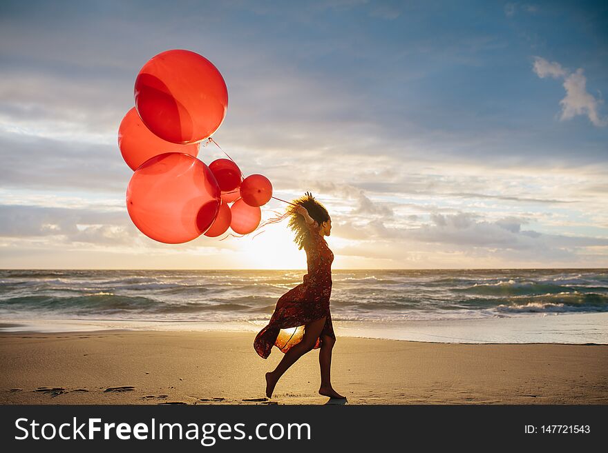 Woman running on the beach with balloons