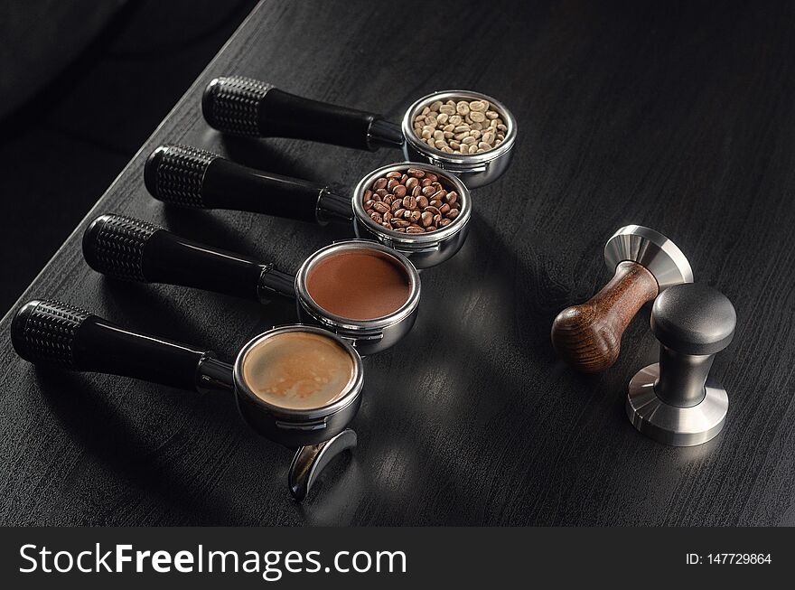 Four holders with green, roasted, ground, and hot coffee and tamper, equipment for making freshly brewed coffee.