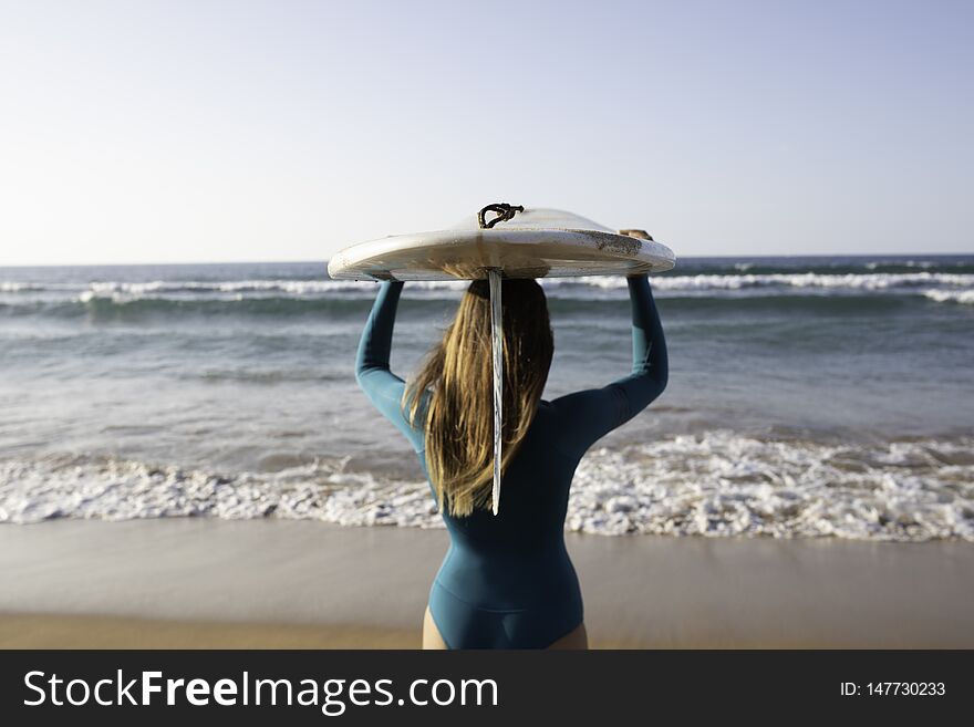 A girl carrying a board on her head on the way to the sea. A girl carrying a board on her head on the way to the sea