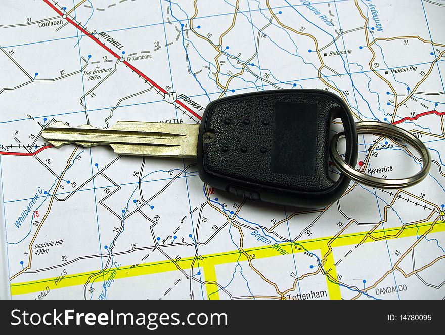 A single car key sitting on a road map background. A single car key sitting on a road map background