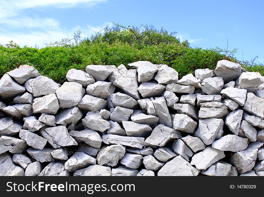 Traditional mediterranean stone wall with thick green bush. Traditional mediterranean stone wall with thick green bush