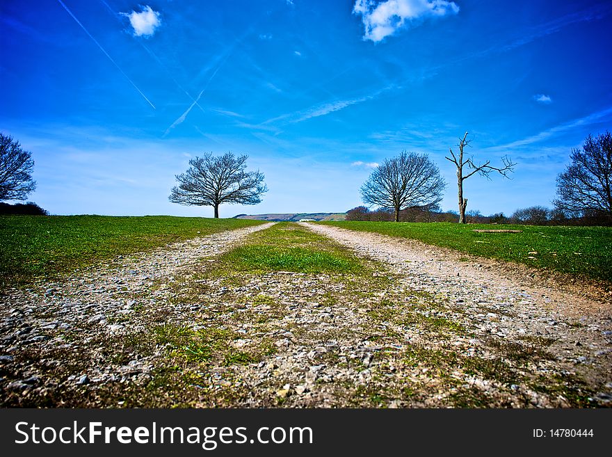 Track receding through countryside with blue sky and cloudscape background. Track receding through countryside with blue sky and cloudscape background.