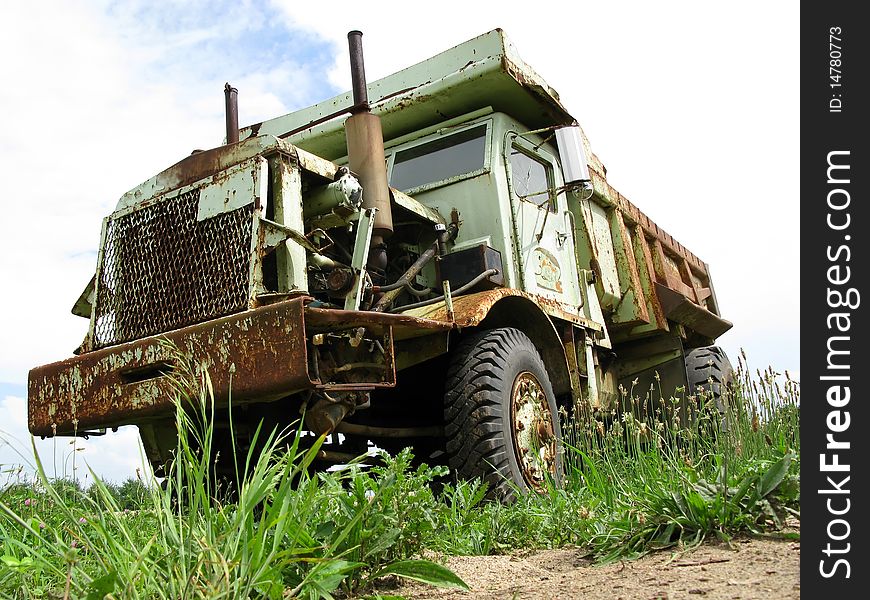 Large rusty dump truck sitting unused and broken in grass field. Large rusty dump truck sitting unused and broken in grass field.