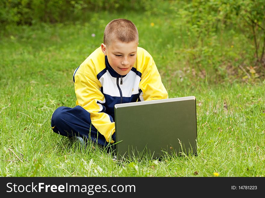 The boy with the computer on a grass