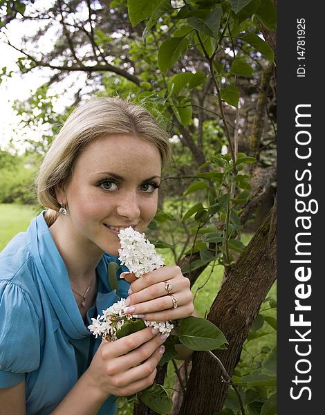 Beautiful blond girl smelling lilac blossoms