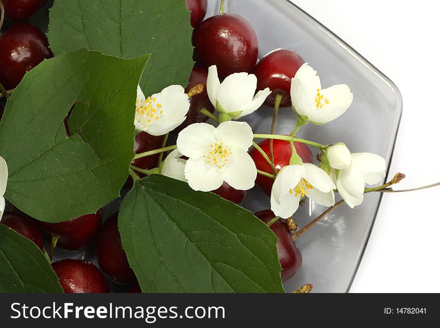 Heap of sweet cherries on a plate with white flowers