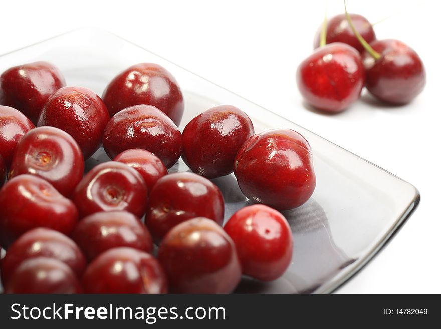 Heap of sweet cherries in a glass plate isolated on white