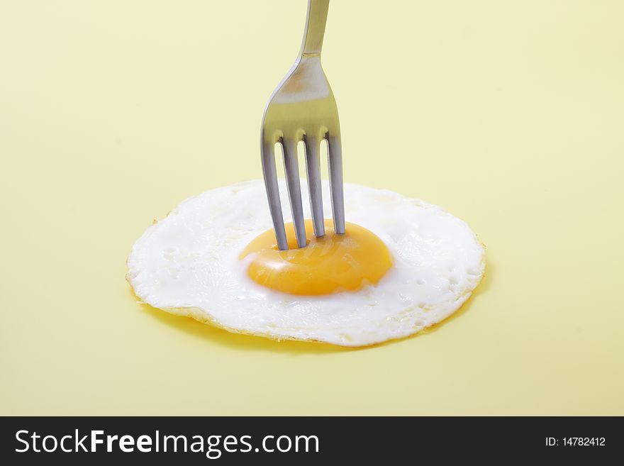 Isolated egg on yellow with fork_