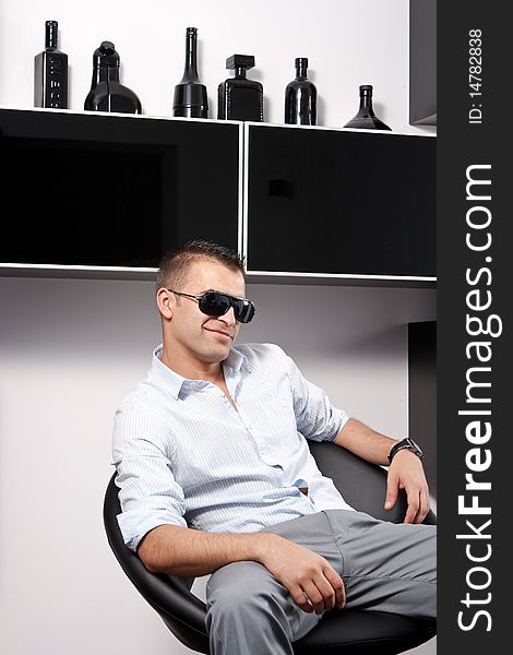 Young man with sunglasses sitting on an armchair