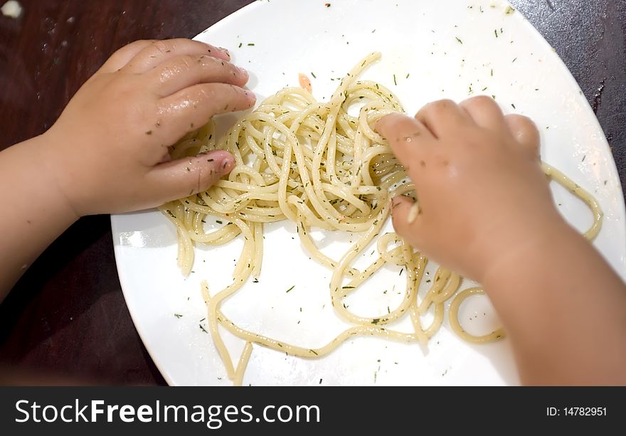 A eating baby to grab pasta