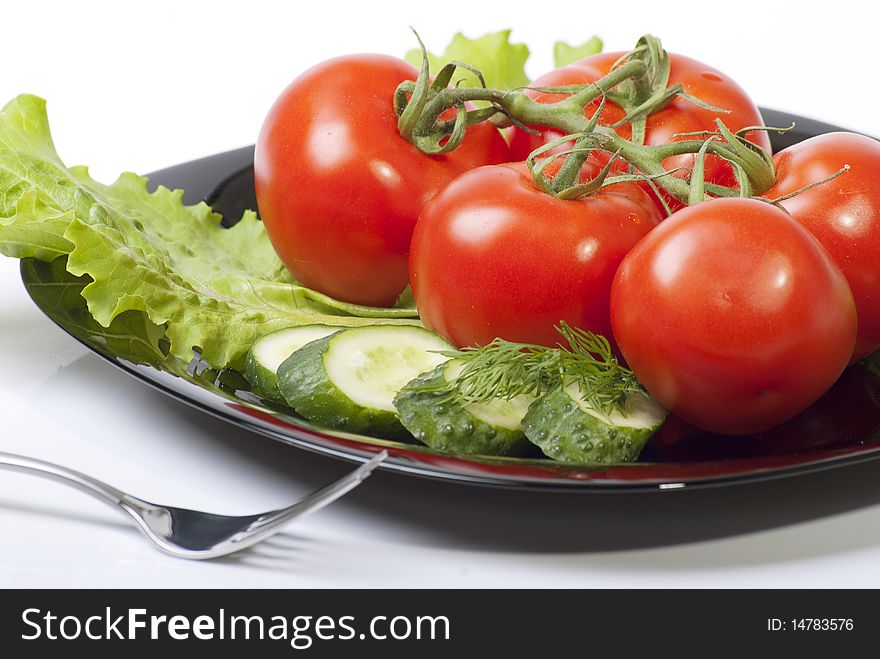 Studio shot of Fresh Vegetables with tomatos salad and cucumber in black plenty isolated on white