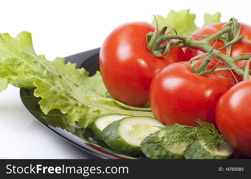 Studio shot of Fresh Vegetables with tomatos salad and cucumber in black plenty isolated on white