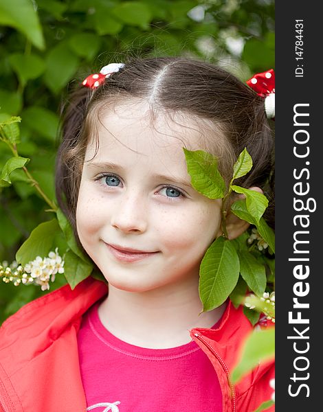 Portrait of a little girl with green leaves and blossom in background. Portrait of a little girl with green leaves and blossom in background.