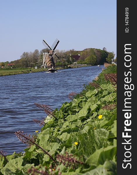 Traditional Dutch windmill alongside a canal. Traditional Dutch windmill alongside a canal.