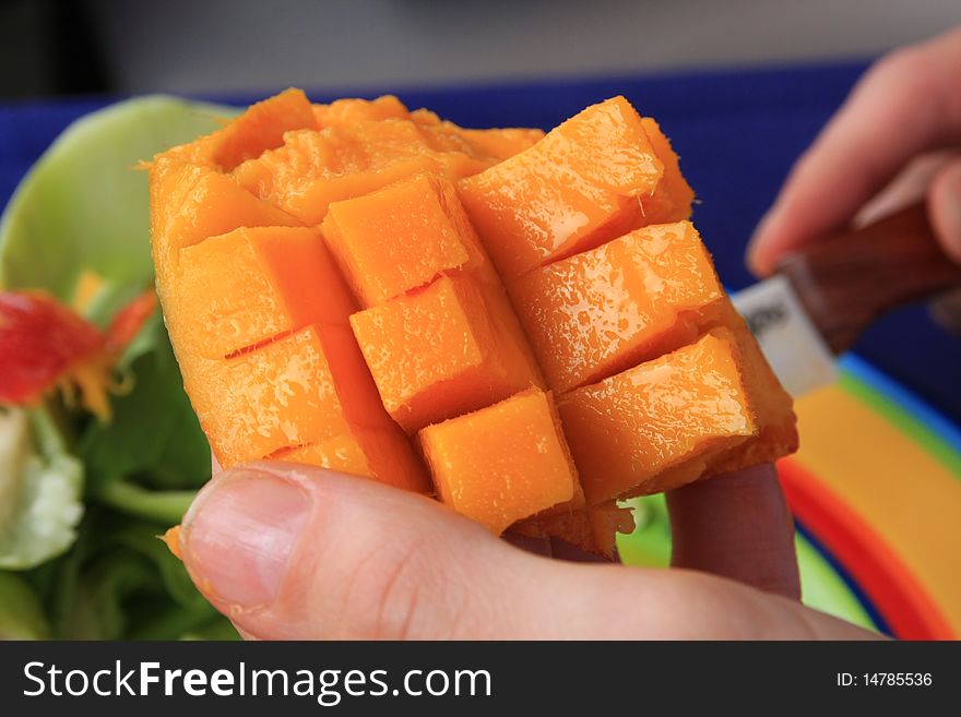 Cross cut mango ready to eat with knife in the background. Cross cut mango ready to eat with knife in the background