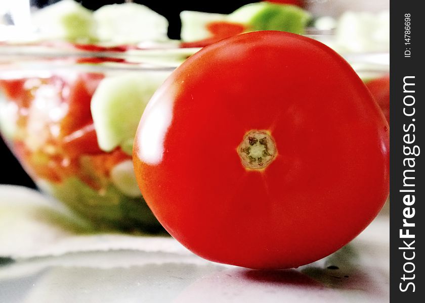 Tomato infront of homemade greek salad. Tomato infront of homemade greek salad