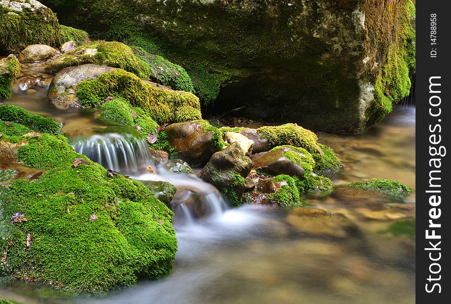 Long exposure shot of the blurred water and green rocks. Long exposure shot of the blurred water and green rocks
