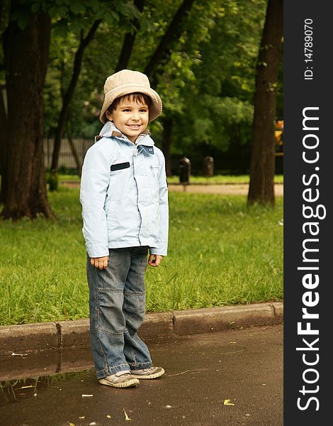 Little cute joyful boy in hat and blue jacket, outdoor shot