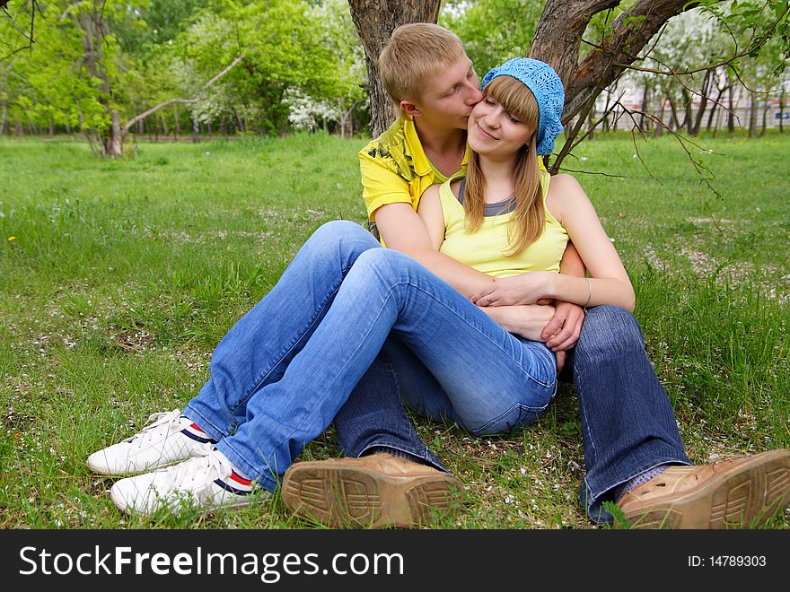 The young guy kisses the beautiful girl in park. The young guy kisses the beautiful girl in park