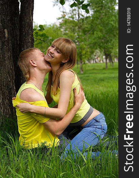 The young guy kisses the beautiful girl in park. The young guy kisses the beautiful girl in park