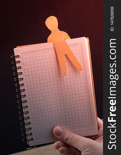 Man shape cut out of paper in notebbok in hand