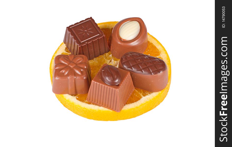 Delicious close up of chocolate candy on orange slice, isolated on white background