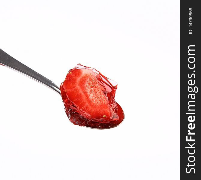 Piece of a strawberries covered with jelly on a spoon