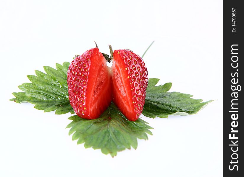 Strawberry on a leaf cut in half on white background