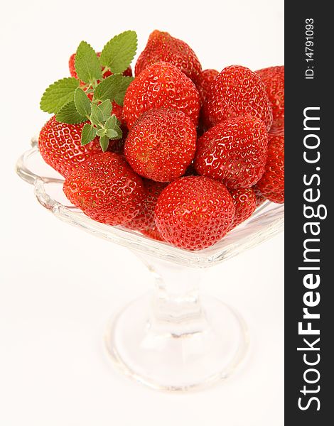 Strawberries in a cup decorated with a lemon balm twig on white background