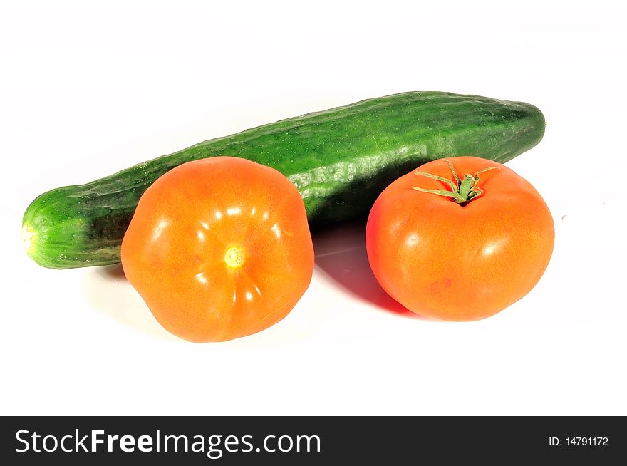 In the photo isolated on a white background is a vegetable cucumber and two tomatoes. In the photo isolated on a white background is a vegetable cucumber and two tomatoes.