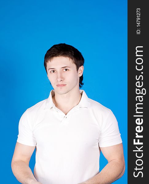 A brave young man on a blue background with a white shirt in the studio. A brave young man on a blue background with a white shirt in the studio
