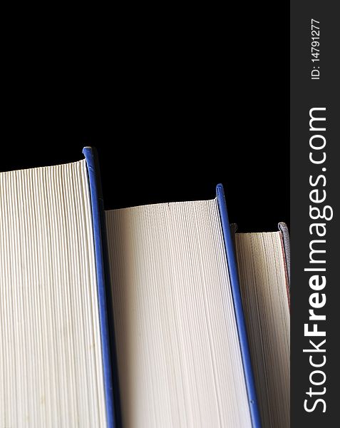A stack of thick hardcover textbooks isolated on pitch black background. A stack of thick hardcover textbooks isolated on pitch black background