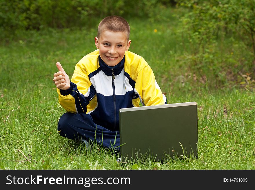 The boy with the computer on a grass